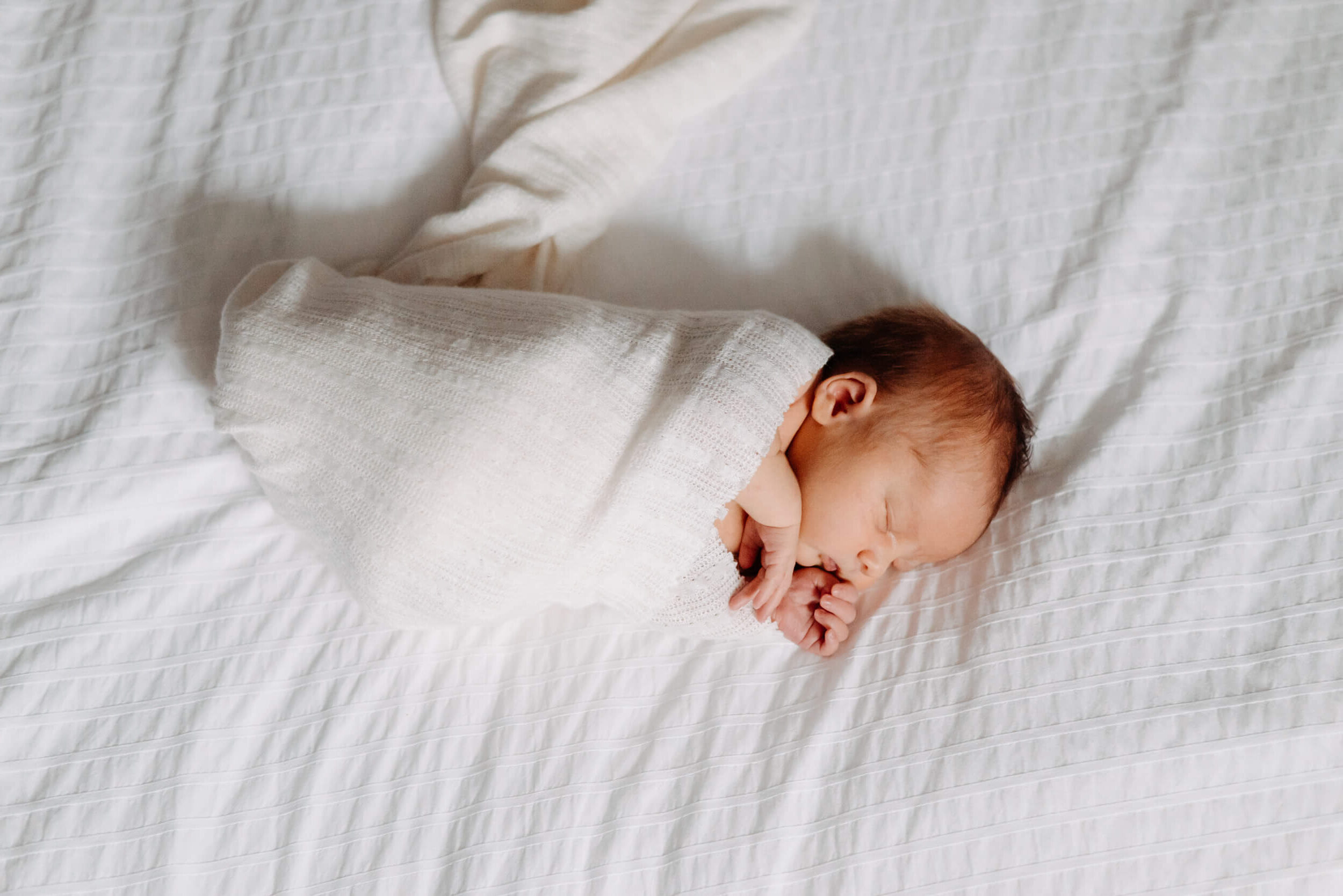 newborn lying on white bed, Kelowna newborn photography