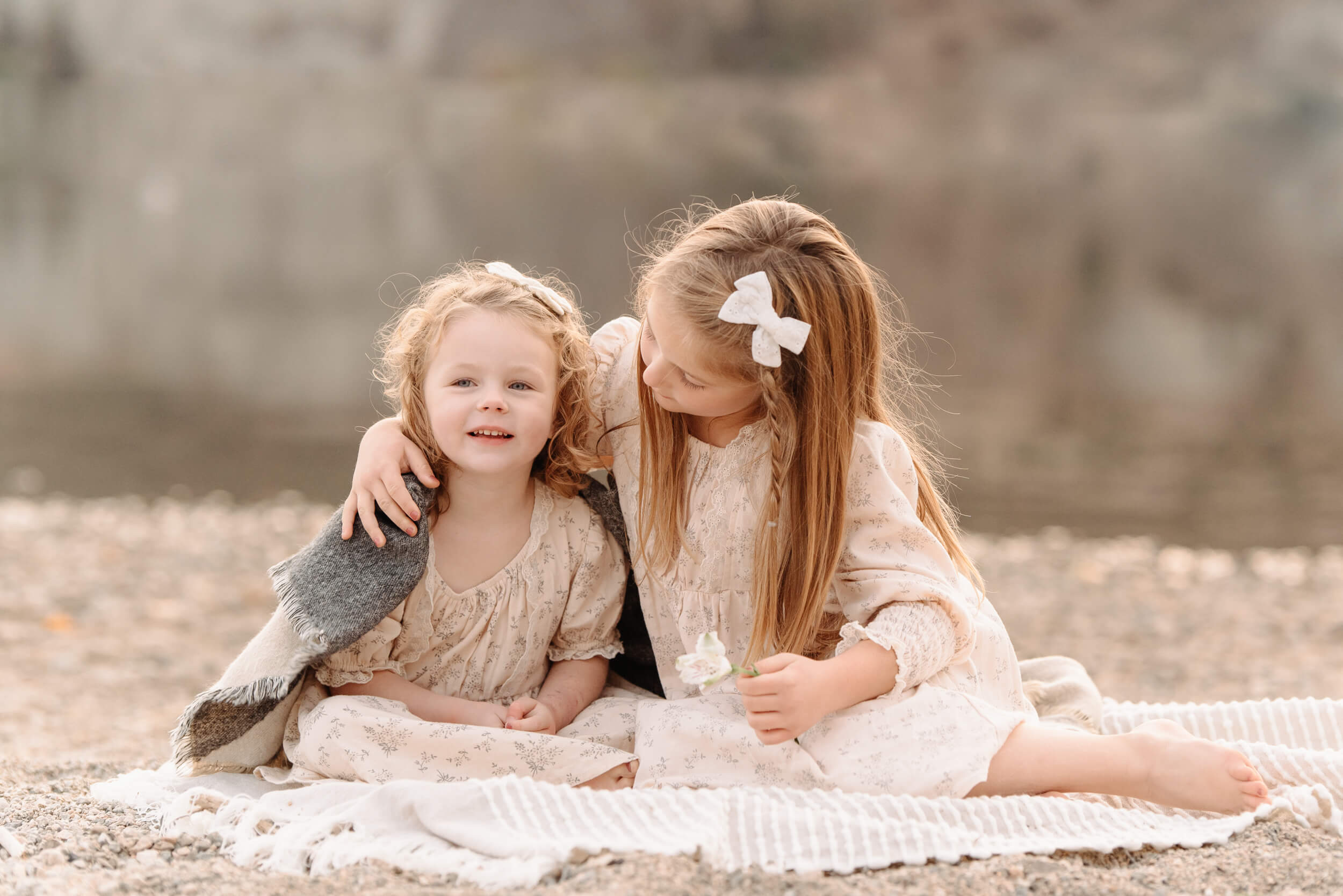 sisters cuddling on beach
