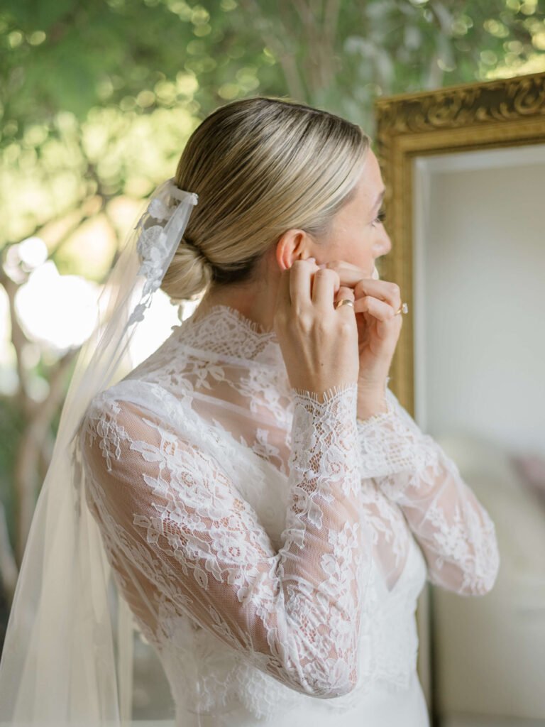 bride puts in earring after getting hair and makeup done in kelowna