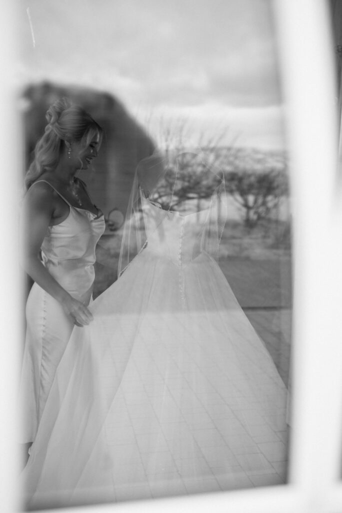 bride looks at dress through window after getting hair and makeup done in kelowna