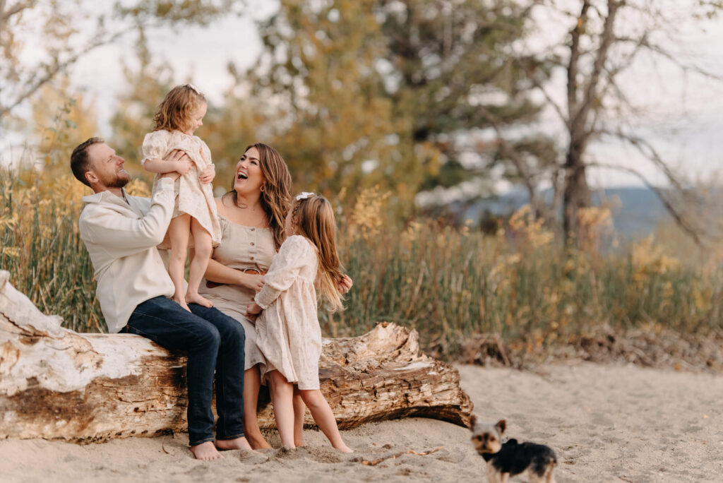 family sitting on a log at the beach