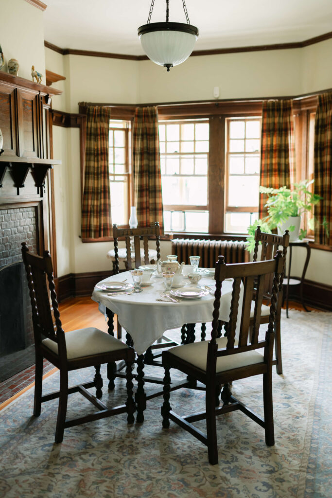 Table set for tea with 4 chairs around in front of a paned glass window and fireplace at the mackie lakehouse vernon wedding venue