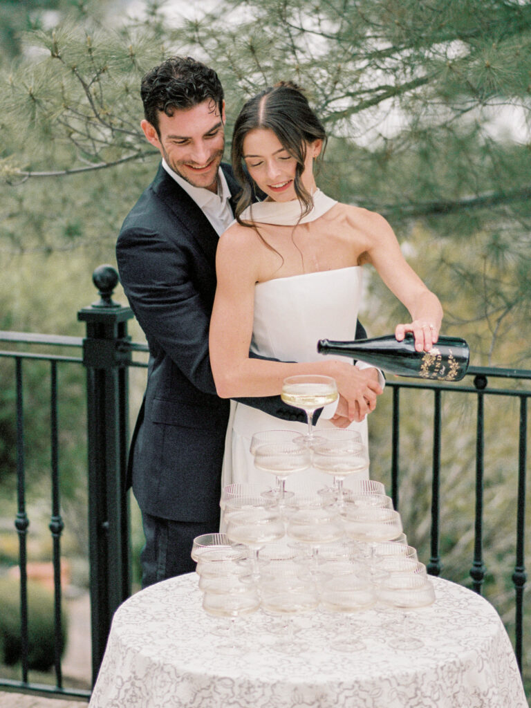 bride pours champagne at a champagne tower at a welcome dinner at a chateau okanagan wedding
