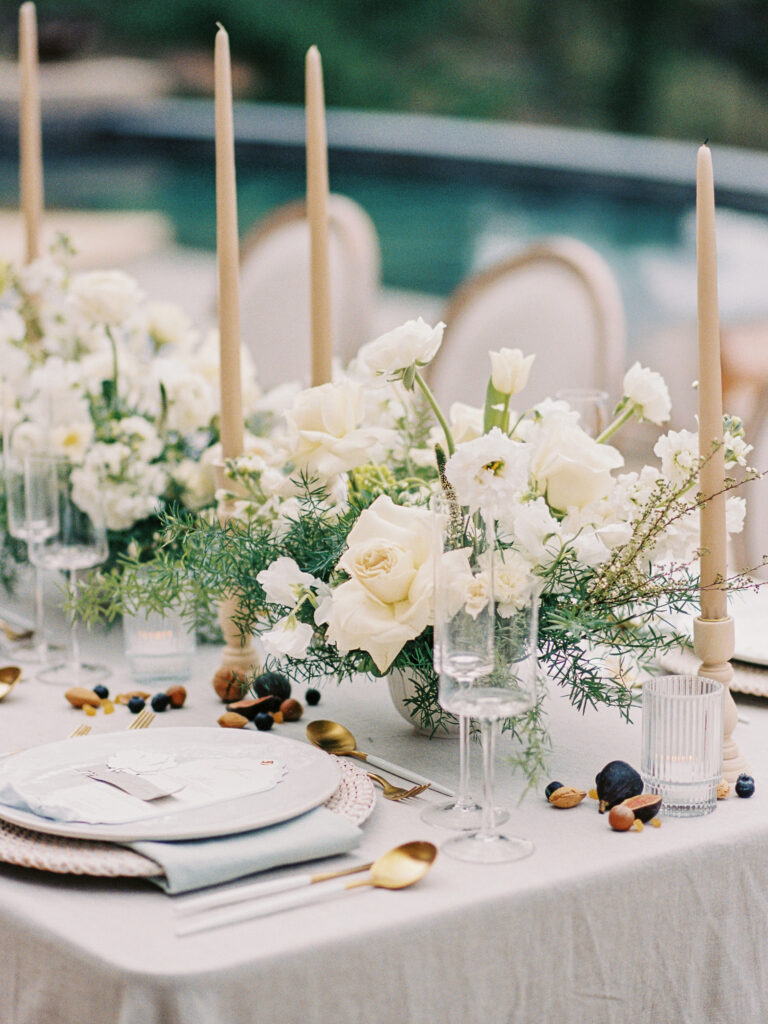 tablescape featuring white florals, peach candlesticks and fruits at a chateau okanagan wedding welcome dinner